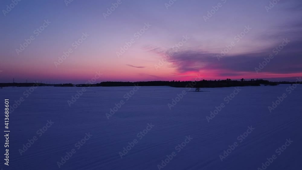 Beautiful aerial view of winter landscape after vibrant sunset, purple high contrast sky, snow covered field, wide angle drone shot moving forward slow Beautiful aerial view of winter landscape after vibrant sunset, purple high contrast sky, snow covered field, wide angle drone shot moving forward slow