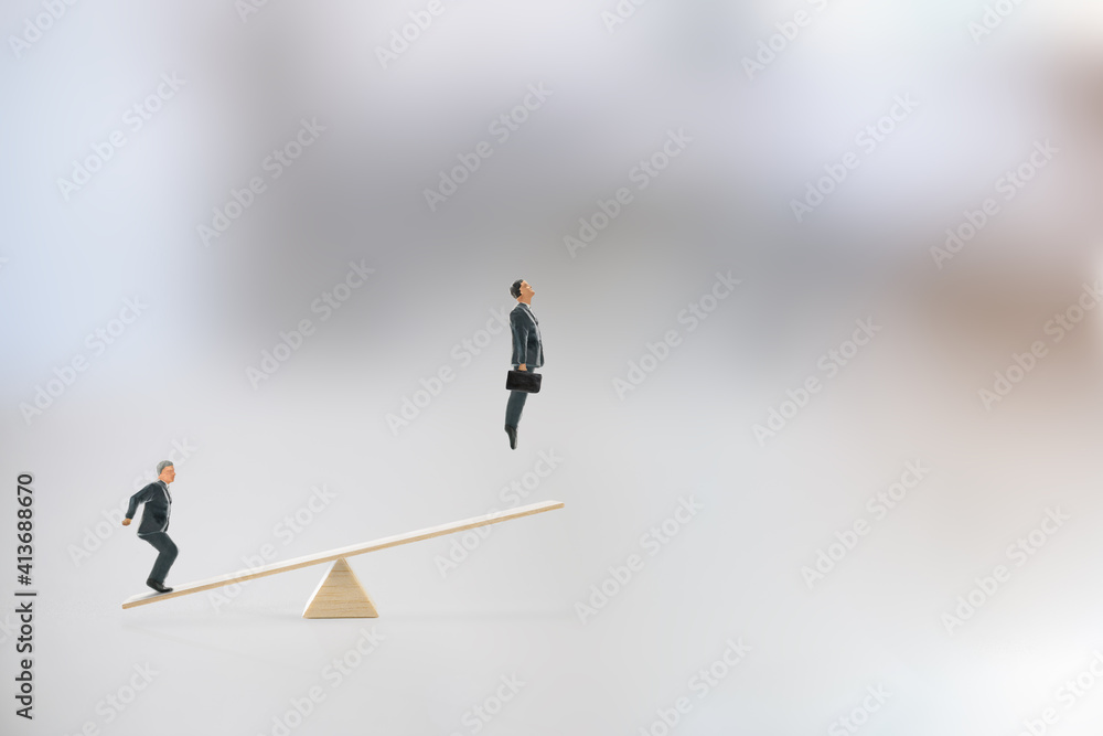 Business partnership and cooperation for ultimate success, motivation concept : Colleague steps on a seesaw sending a friend flying high above into the air, depicts team spirit for getting a job done Business partnership and cooperation for ultimate success, motivation concept : Colleague steps on a seesaw sending a friend flying high above into the air, depicts team spirit for getting a job done