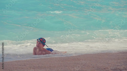 Young boy plays with water waves on the beach photo