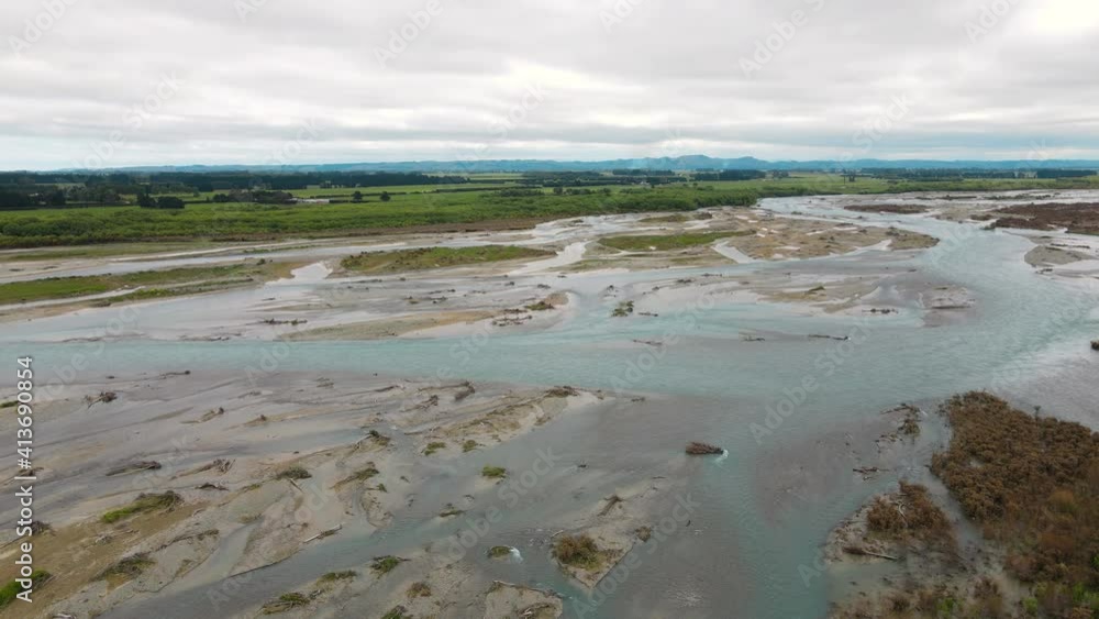 Aerial drone view of a large glacial riverbed beside green farmland. Aerial drone view of a large glacial riverbed beside green farmland.