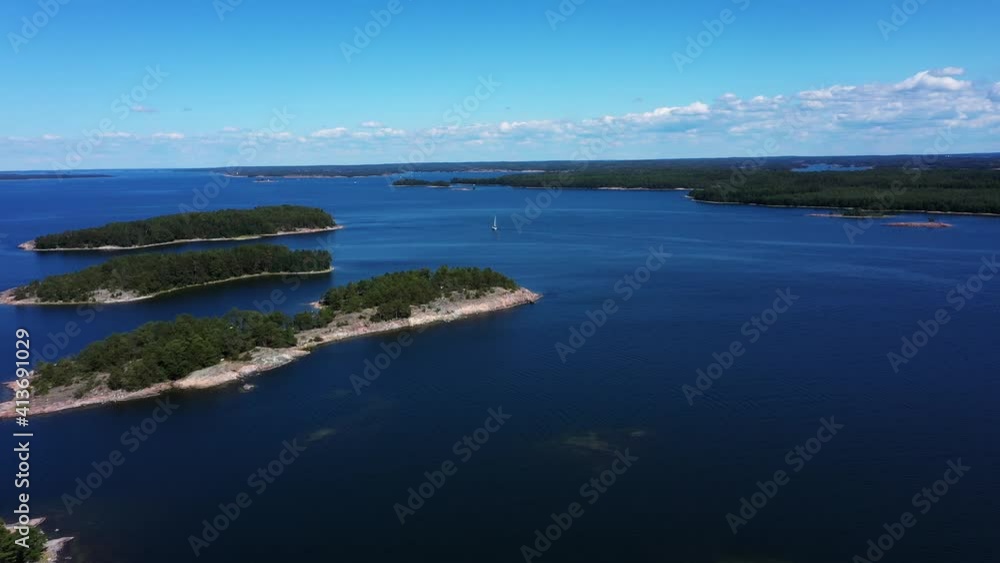 Aerial view over islands, towards a sailboat, sailing on the seas of the Finnish Archipelago, sunny day, in Finland - dolly, drone shot Aerial view over islands, towards a sailboat, sailing on the seas of the Finnish Archipelago, sunny day, in Finland - dolly, drone shot