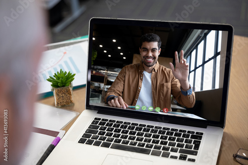 Smiling mixed race businessman displayed on laptop screen during office video call
