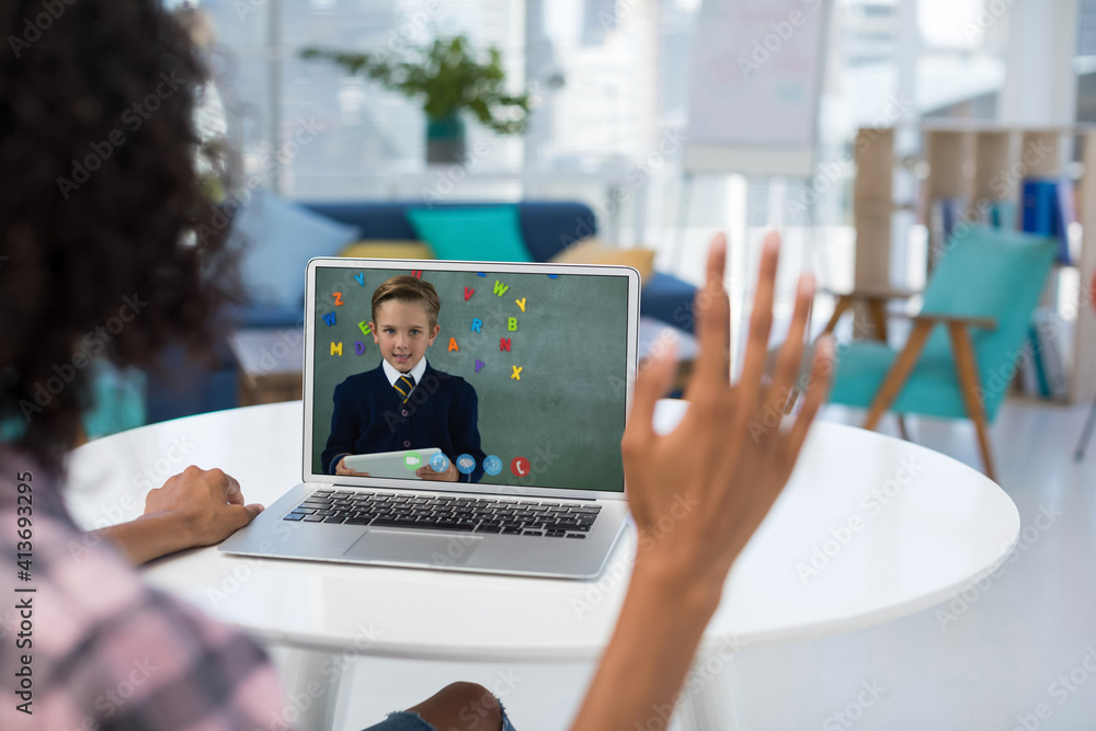 Mixed race female teacher using laptop and waving on video call with schoolboy Mixed race female teacher using laptop and waving on video call with schoolboy