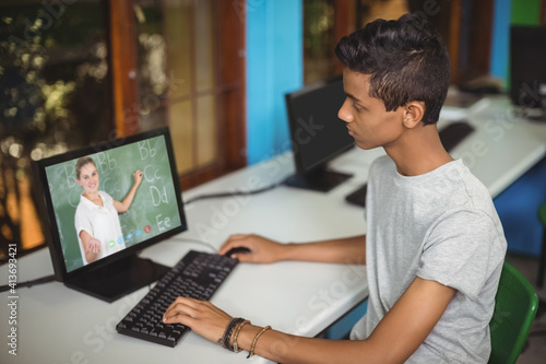 Mixed race schoolboy using computer on video call with female teacher