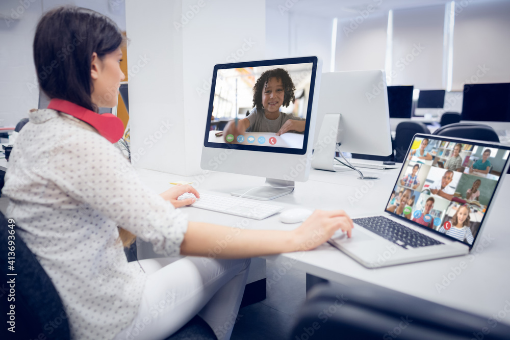 Caucasian female teacher using computer and laptop on video call with school children Caucasian female teacher using computer and laptop on video call with school children