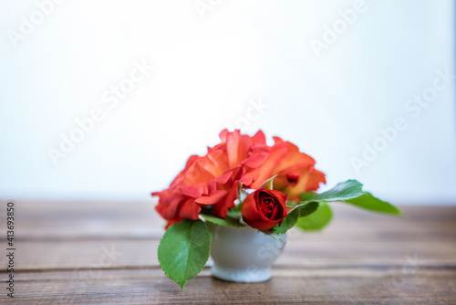 Fototapeta Naklejka Na Ścianę i Meble -  bouquet of small red roses in a vase on a wooden background