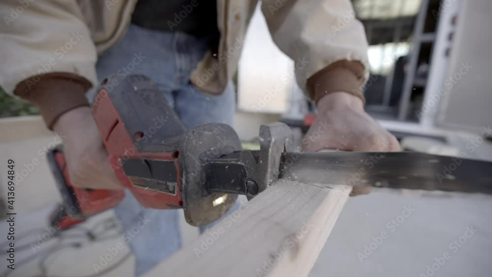 Slow motion close up, cordless reciprocating straight saw cutting plank Slow motion close up, cordless reciprocating straight saw cutting plank