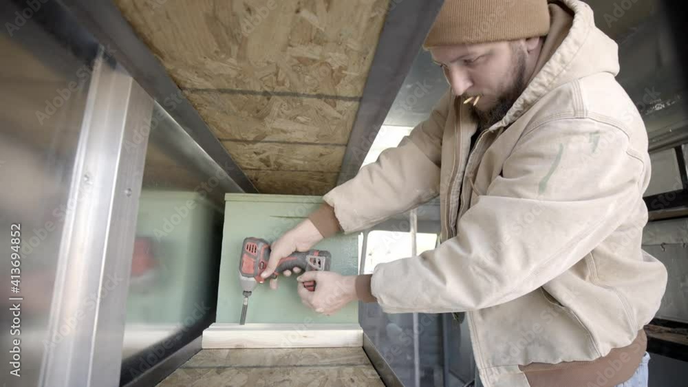 Contractor installing shelves with cordless drill, static shot Contractor installing shelves with cordless drill, static shot