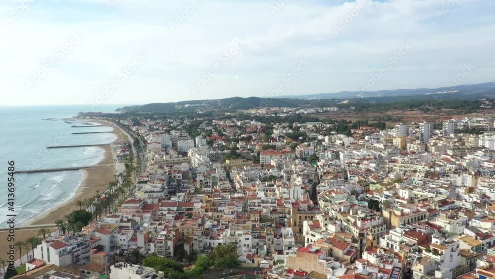 AERIAL: Wide shot of the beach, piers and buildings in Sitges, Spain AERIAL: Wide shot of the beach, piers and buildings in Sitges, Spain