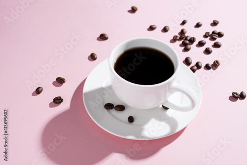  Cup of coffee with beans at pink background