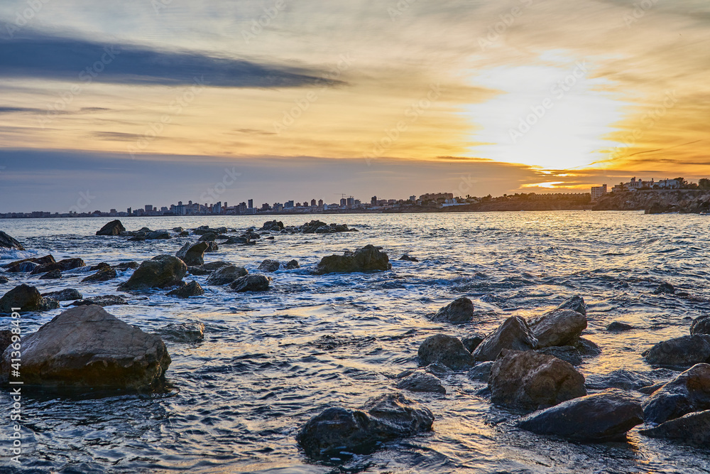 Obraz premium landscape on the beach of warm colors at sunset with a city behind