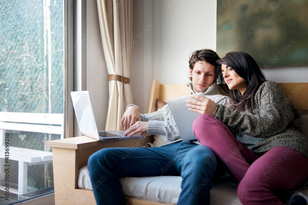 Woman showing digital tablet to boyfriend on sofa at home Woman showing digital tablet to boyfriend on sofa at home