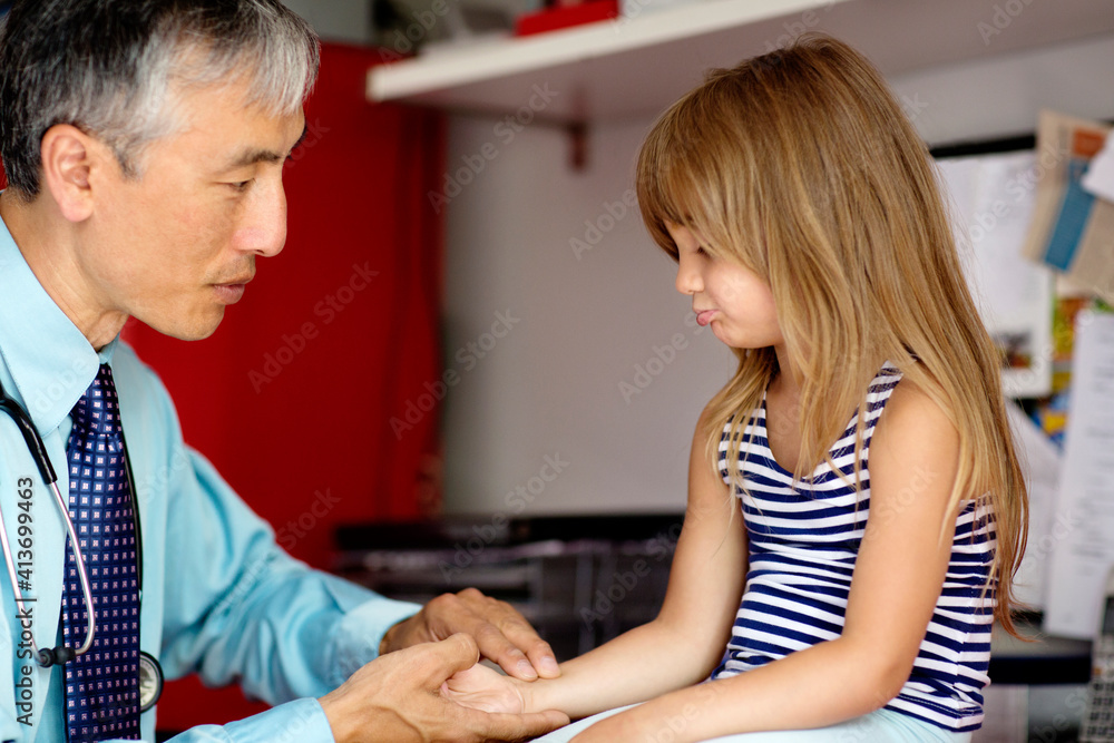 Doctor examining girl while holding her hand at home Doctor examining girl while holding her hand at home