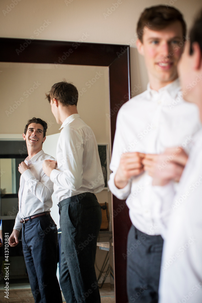 Gay couple looking at each other while getting dressed at home Gay couple looking at each other while getting dressed at home