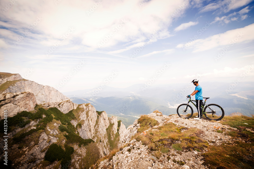 Side view of mountain biker with bicycle against cloudy sky Side view of mountain biker with bicycle against cloudy sky