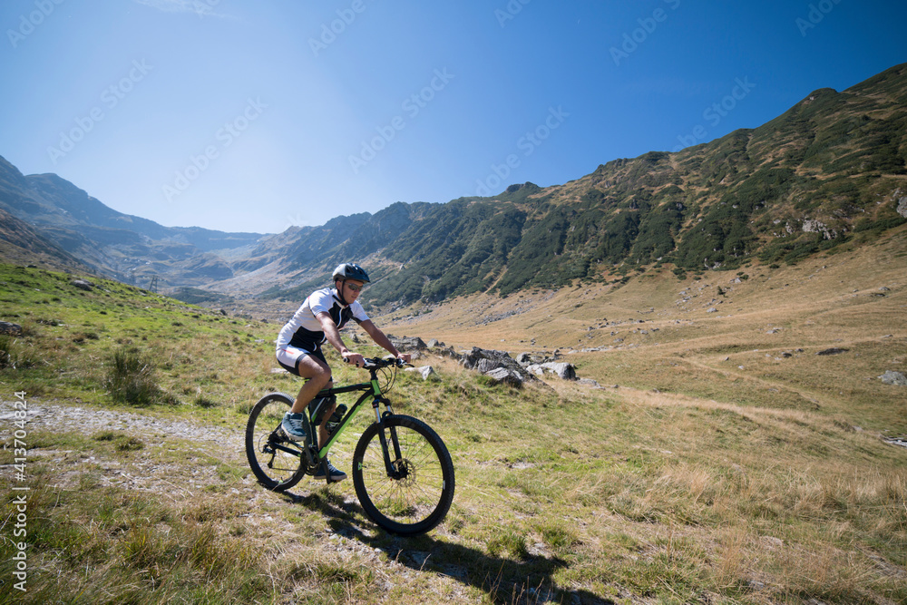 Man riding bicycle on grass field against mountains Man riding bicycle on grass field against mountains