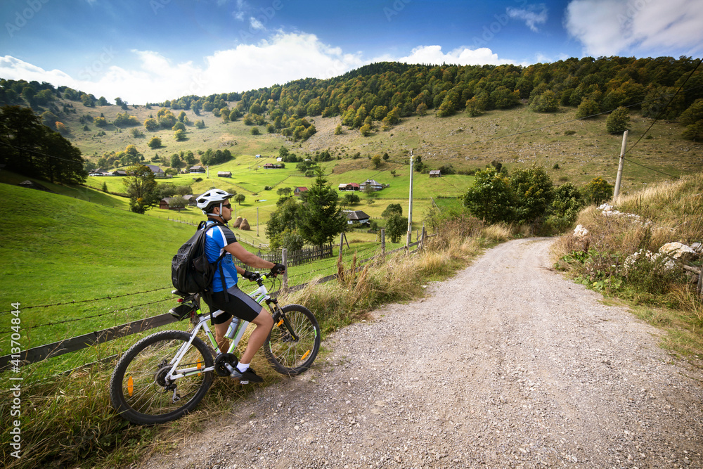 Male athlete with bicycle on dirt road by field Male athlete with bicycle on dirt road by field