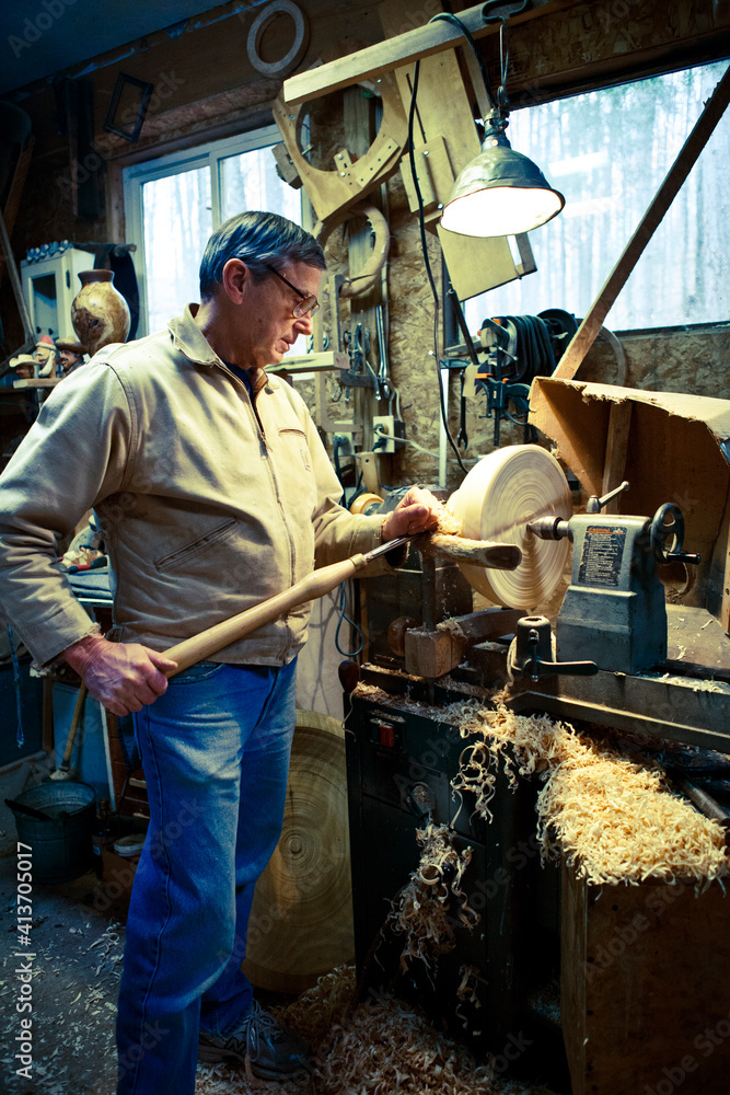 Carpenter carving wood with chisel on lathe at workshop