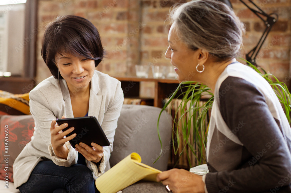 Businesswoman showing tablet computer to colleagues while sitting in office Businesswoman showing tablet computer to colleagues while sitting in office