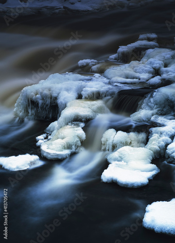 Frozen and icy streams filled with cold spring water flowing through the rural countryside of South Eastern Ontario Canada, full scenic landscapes featuring natural phenomena.