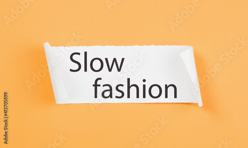 Slow Fashion text on tirn notice paper on plain yellow background. Sustainable approach to manufacturing and eco-friendly anti-consumerism concept. Conscious buying awareness. Copy space