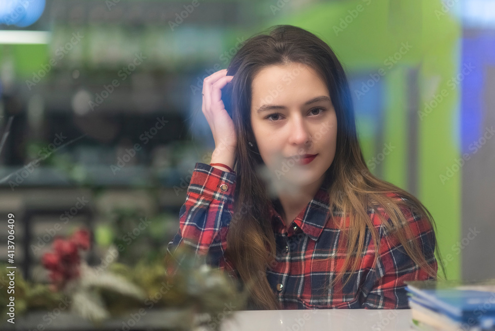 Portrait of a girl behind glass in a cafe. The girl is out of focus.