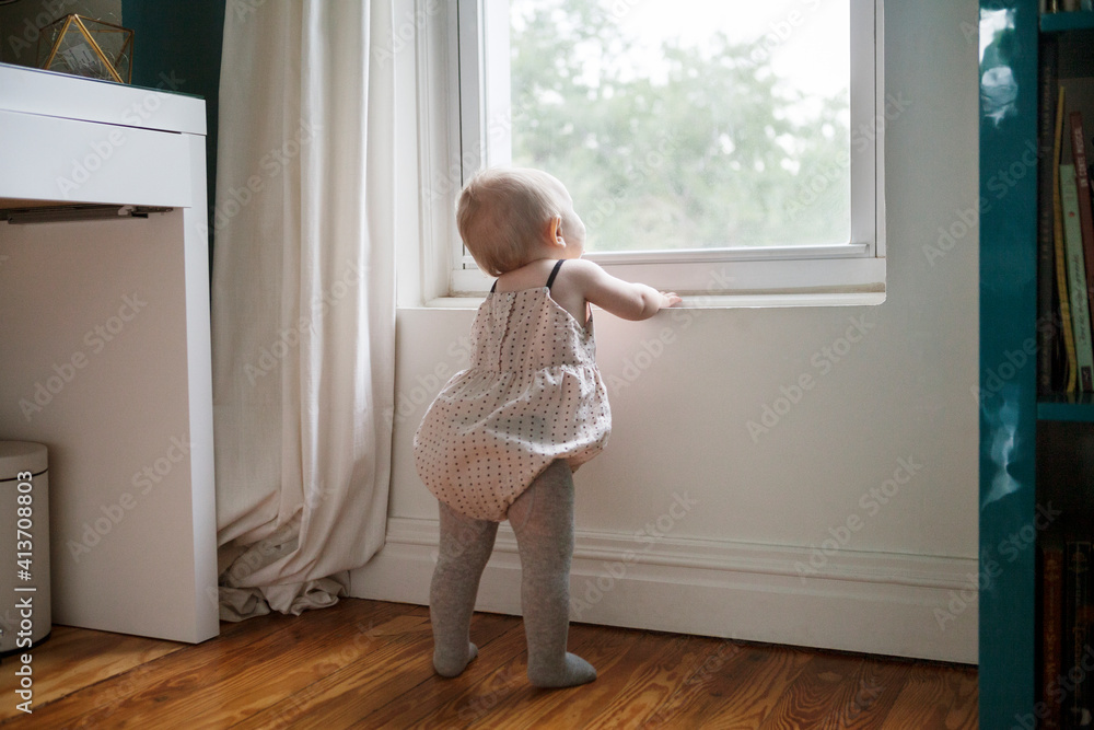 Rear view of baby girl looking through window Rear view of baby girl looking through window