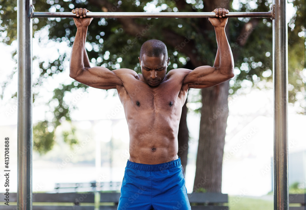Male athlete exercising on metal bar in park Male athlete exercising on metal bar in park