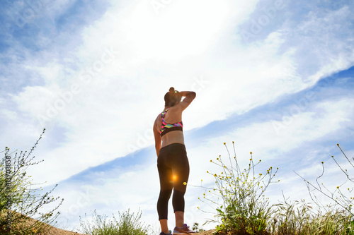 Rear view of woman standing on hill against sky photo