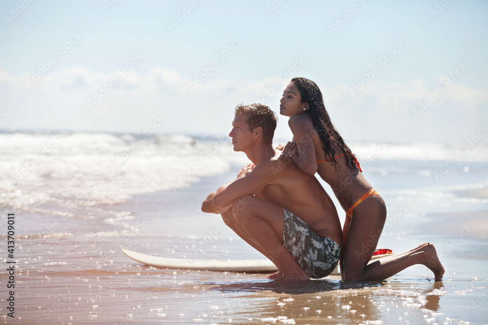 Side view of couple with surfboard at shore on sunny day Side view of couple with surfboard at shore on sunny day