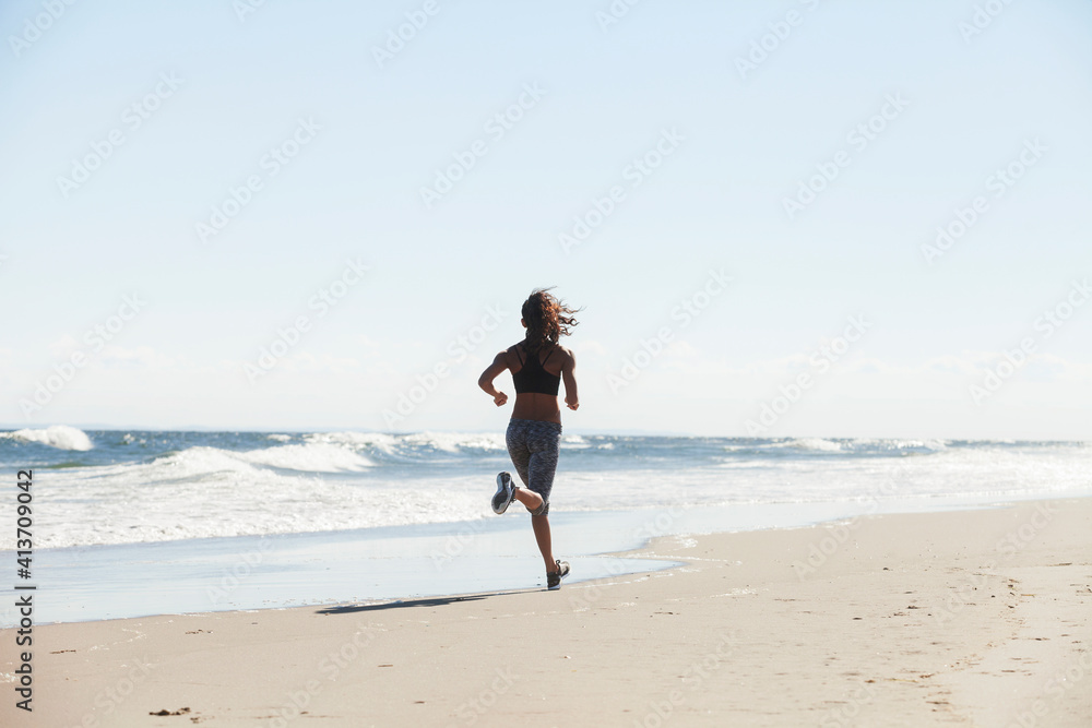 Rear view of woman running at beach on sunny day Rear view of woman running at beach on sunny day