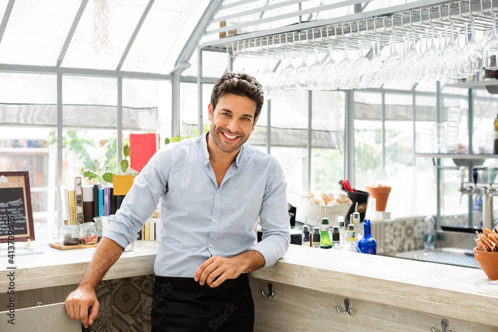 Portrait of confident bartender standing at counter in restaurant