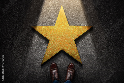 Success in Business or Personal Talent Concept. Top View of Business Person in Working Shoes Standing in front of a Golden Star. Light Shining on the Dark Cement Floor photo