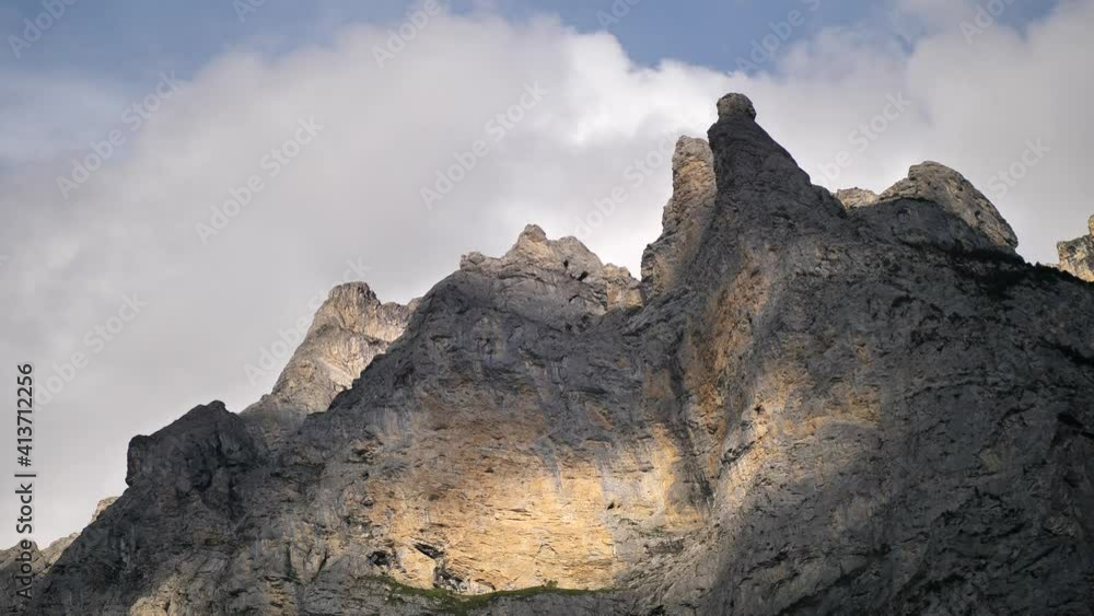 Clouds moving on the background of the bare tops of a mountain in Lauterbrunnen Switserland while the sun and shadows are reflected. Wide shot Clouds moving on the background of the bare tops of a mountain in Lauterbrunnen Switserland while the sun and shadows are reflected. Wide shot