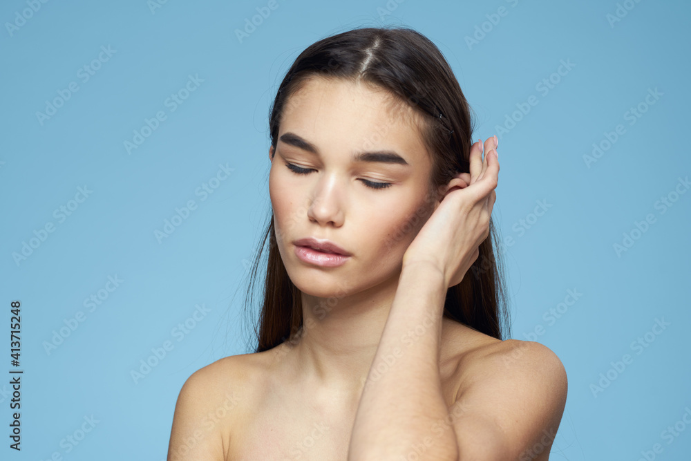 brunette with bare shoulders cosmetics close-up skin care blue background brunette with bare shoulders cosmetics close-up skin care blue background