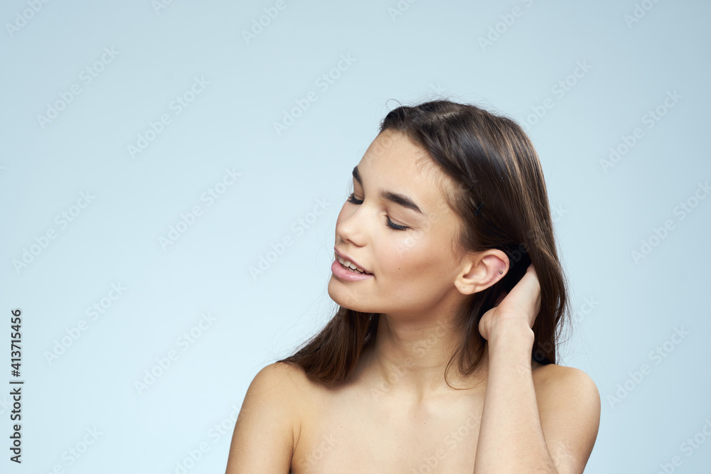 Pretty brunette with bared shoulders long hair body care blue background Pretty brunette with bared shoulders long hair body care blue background