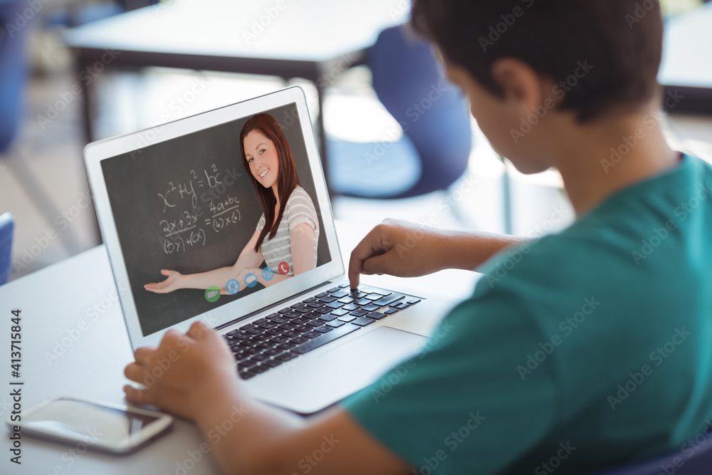 Male caucasian student having a video call with female teacher on laptop at school Male caucasian student having a video call with female teacher on laptop at school