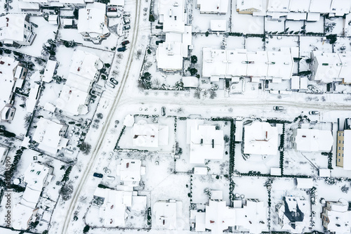 aerial top view of snowy roofs and roads of suburban neighborhood