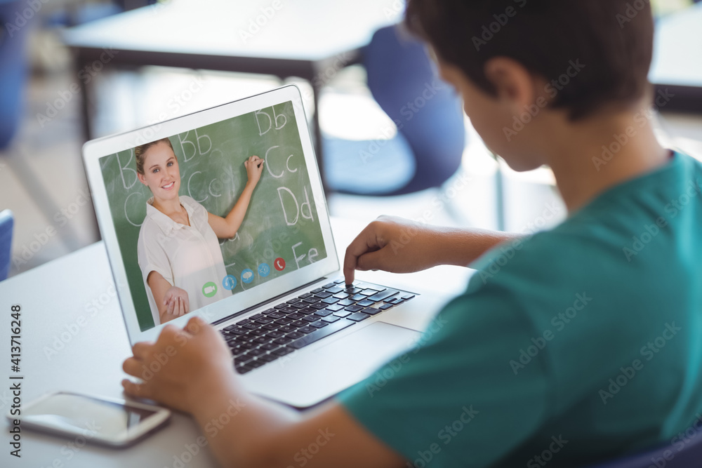 Male caucasian student having a video call with female teacher on laptop at school Male caucasian student having a video call with female teacher on laptop at school