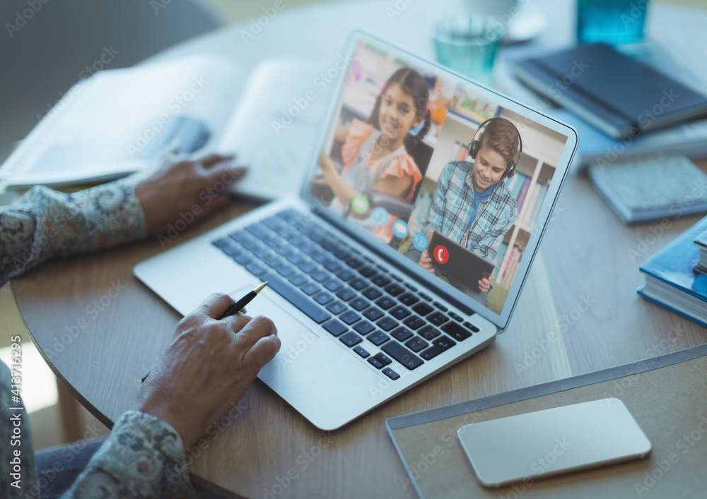 Mid section of female teacher having a video conference with male and female students on laptop at s Mid section of female teacher having a video conference with male and female students on laptop at s