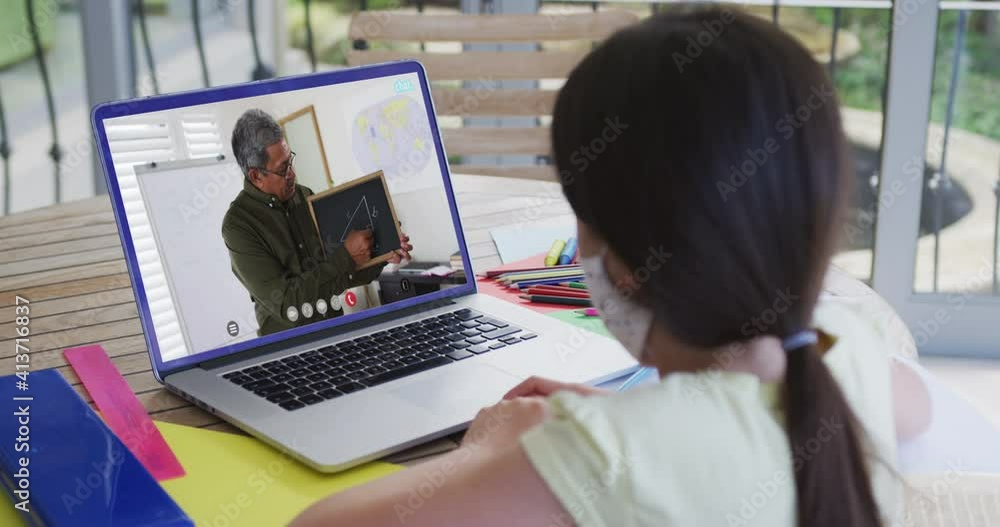 Caucasian schoolgirl in face mask using laptop on video call with male teacher Caucasian schoolgirl in face mask using laptop on video call with male teacher