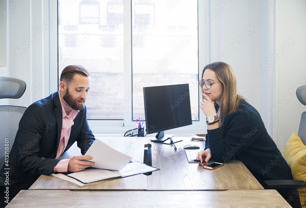 Colleagues discussing paperwork in office Colleagues discussing paperwork in office