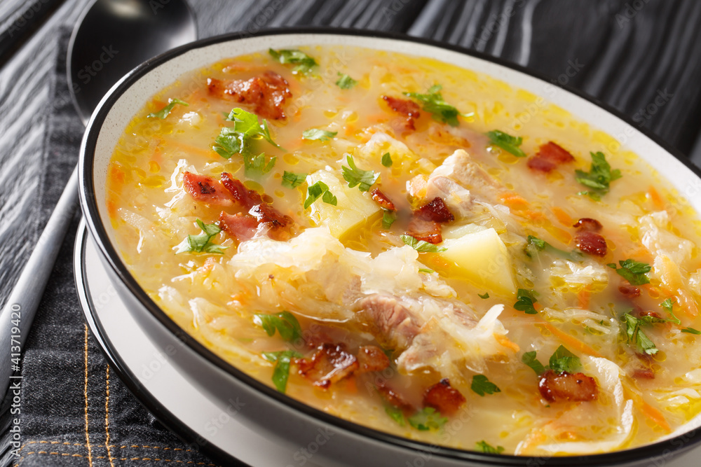 Polish sauerkraut soup Kapusniak with ribs and bacon close-up in a plate on the table. Horizontal