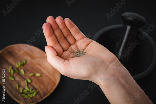 A woman holds a ground cardamom in her hand