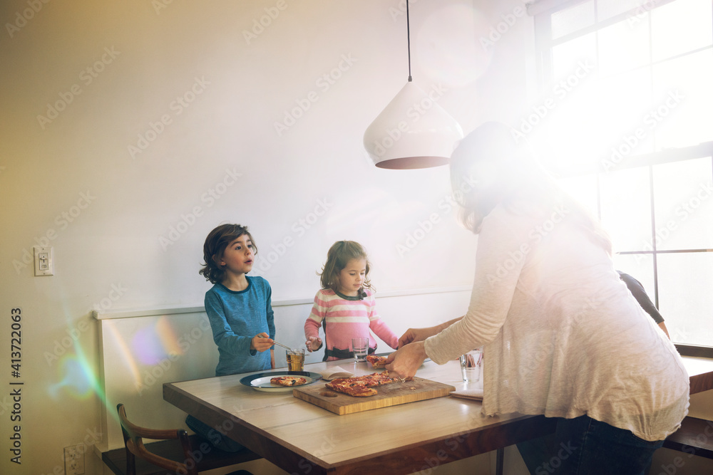 Family eating pizza at dining table in home Family eating pizza at dining table in home