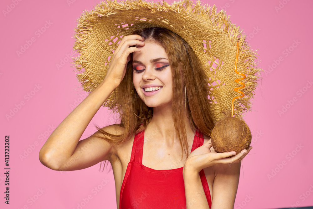 Woman with coconut cocktail in straw hat exotic vacation summer pink background