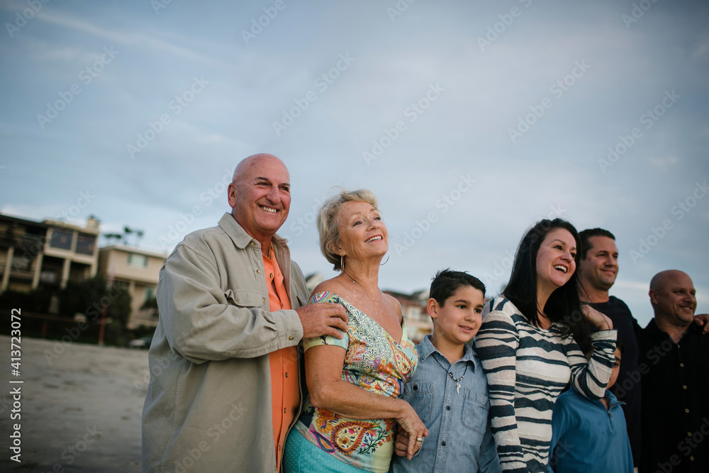 Happy family standing at beach against sky during sunset Happy family standing at beach against sky during sunset