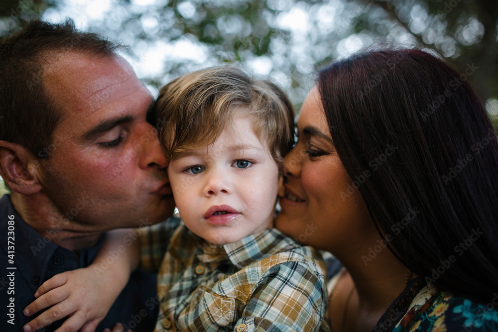 Portrait of cute son with parents kissing on field Portrait of cute son with parents kissing on field