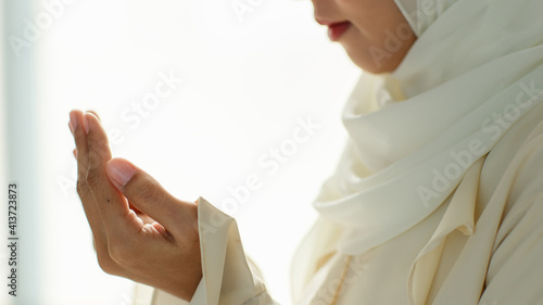 Young and beautiful Asian Muslim woman rise hands and praying with respect and calm manner