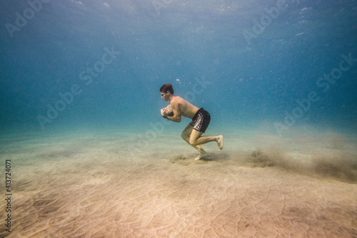 Wallpaper Mural Side view of man with rock running underwater Torontodigital.ca